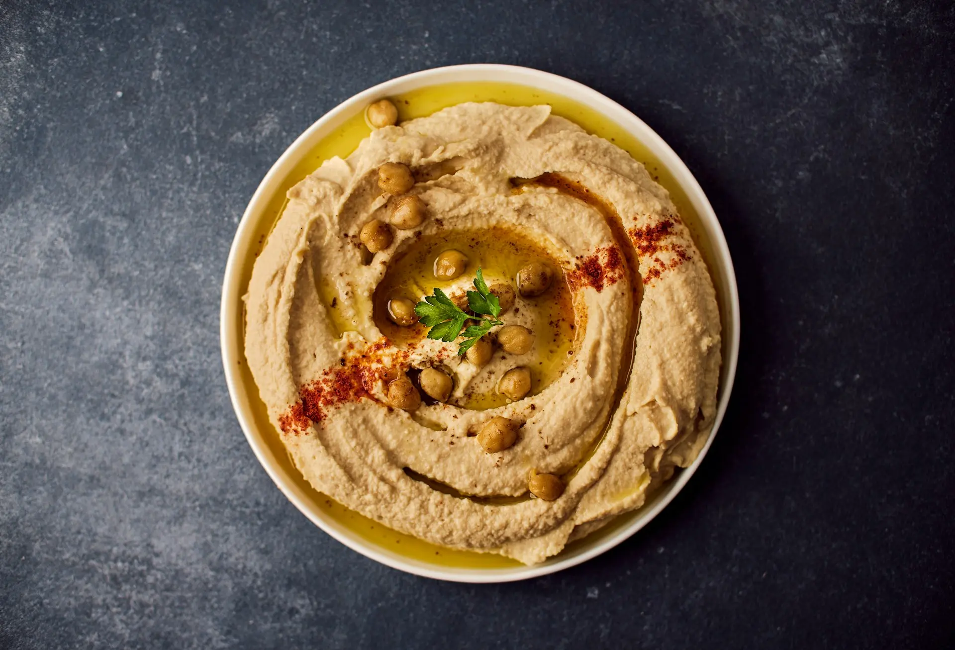a bowl of hummus with a garnish on top